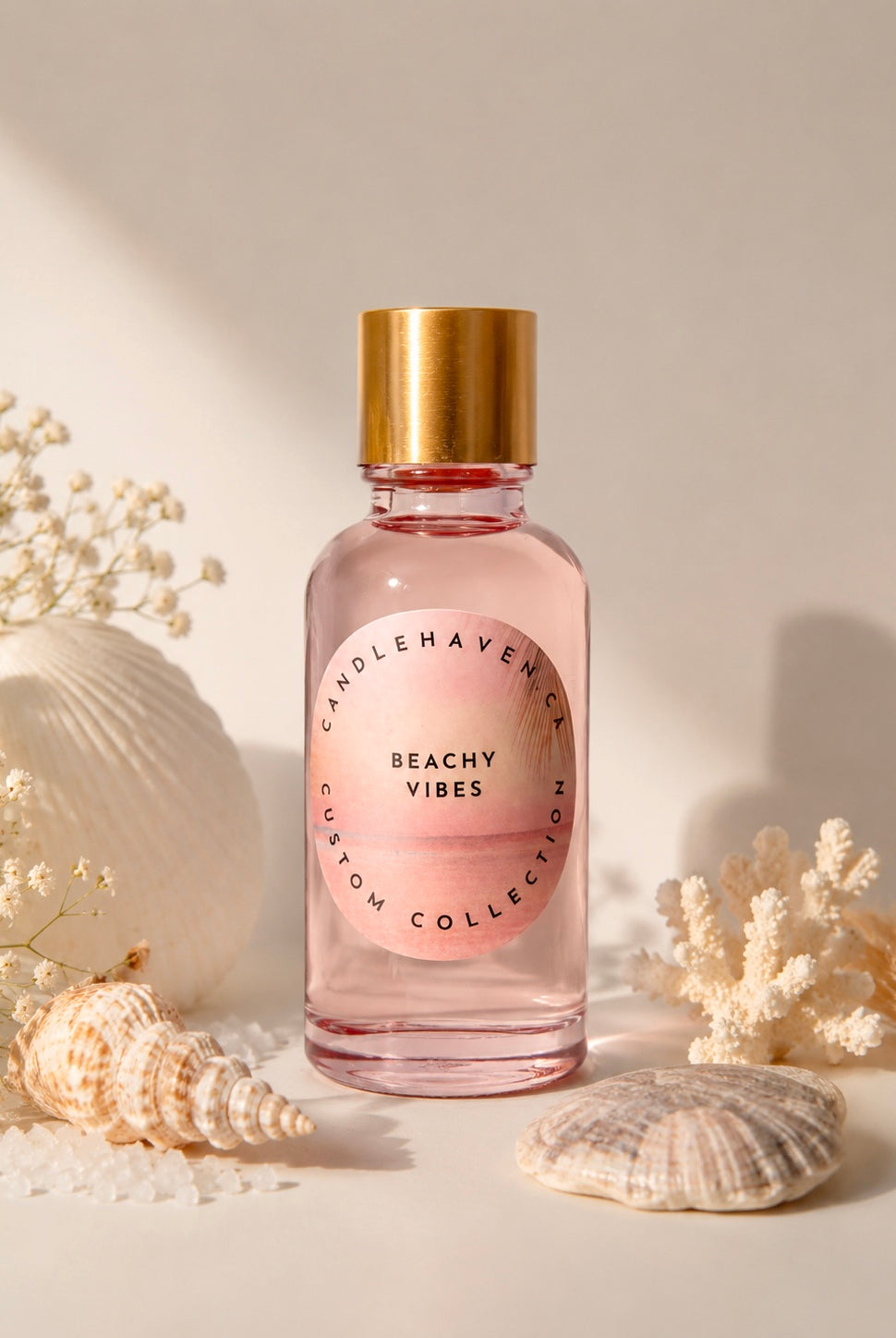 Bottle of 'Beachy Vibes' fragrance oil for candle making by Candlehaven.ca with a gold cap on a light background with shells and flowers.