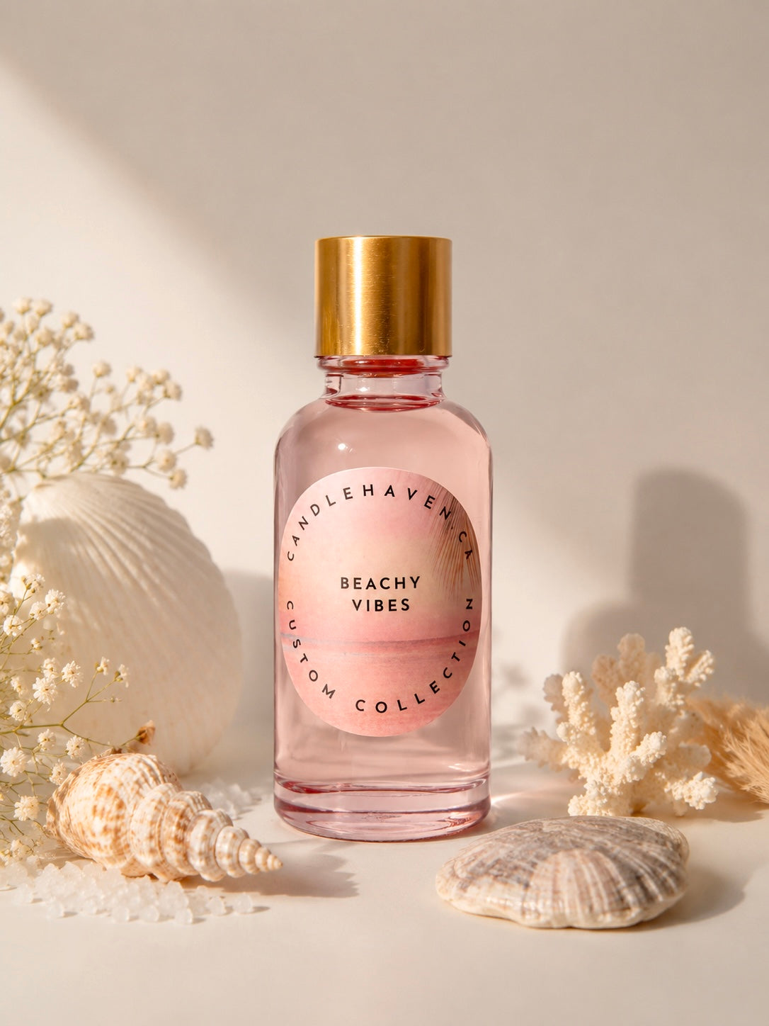Bottle of 'Beachy Vibes' fragrance oil for candle making by Candlehaven.ca with a gold cap on a light background with shells and flowers.