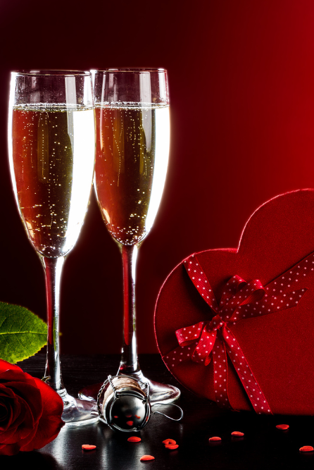 Champagne Toast Fragrance Oil | Two champagne glasses with a red heart-shaped gift box and rose on a dark background