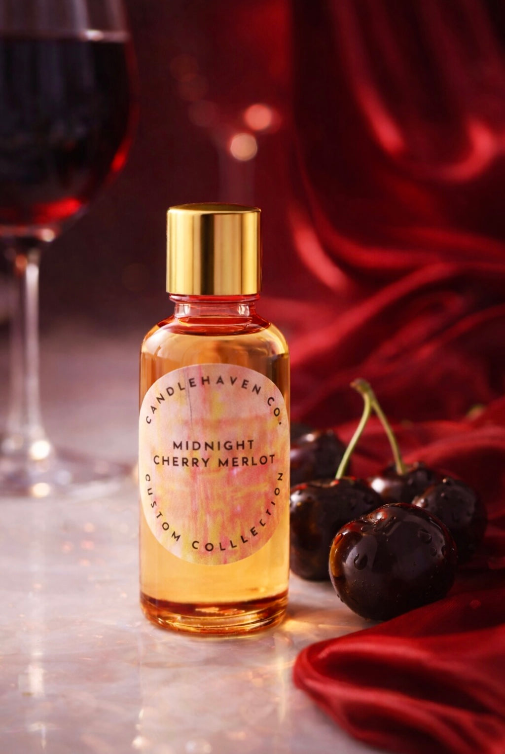 Bottle of Candlehaven’s ‘Midnight Cherry Merlot' candle fragrance oil with cherries and a glass of wine on a red fabric background