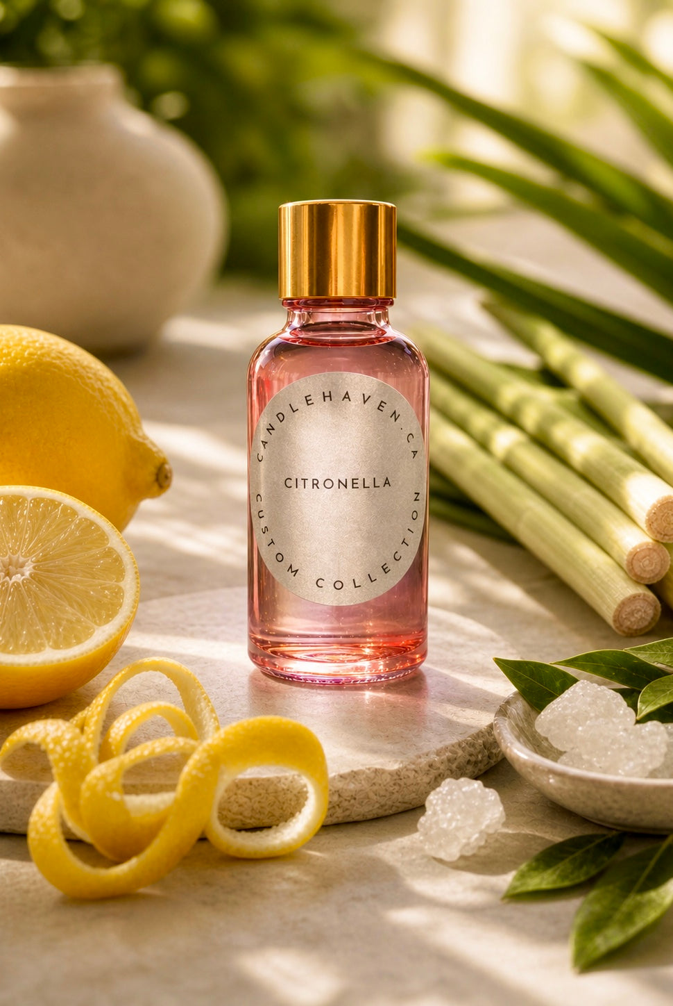Pink bottle of citronella fragrance oil for candle making with lemon peel and lemon grass and camphor in the background