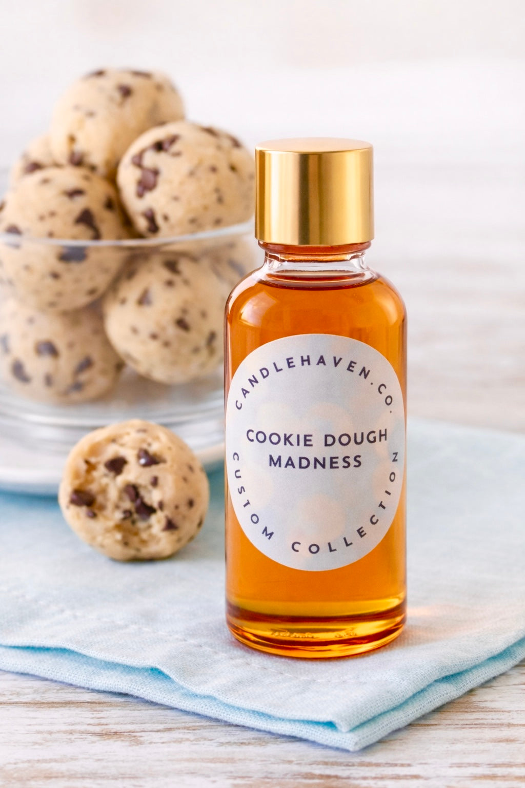 Bottle of 'Cookie Dough Madness' fragrance oil for candles by Candlehaven.ca with cookie dough balls in the background