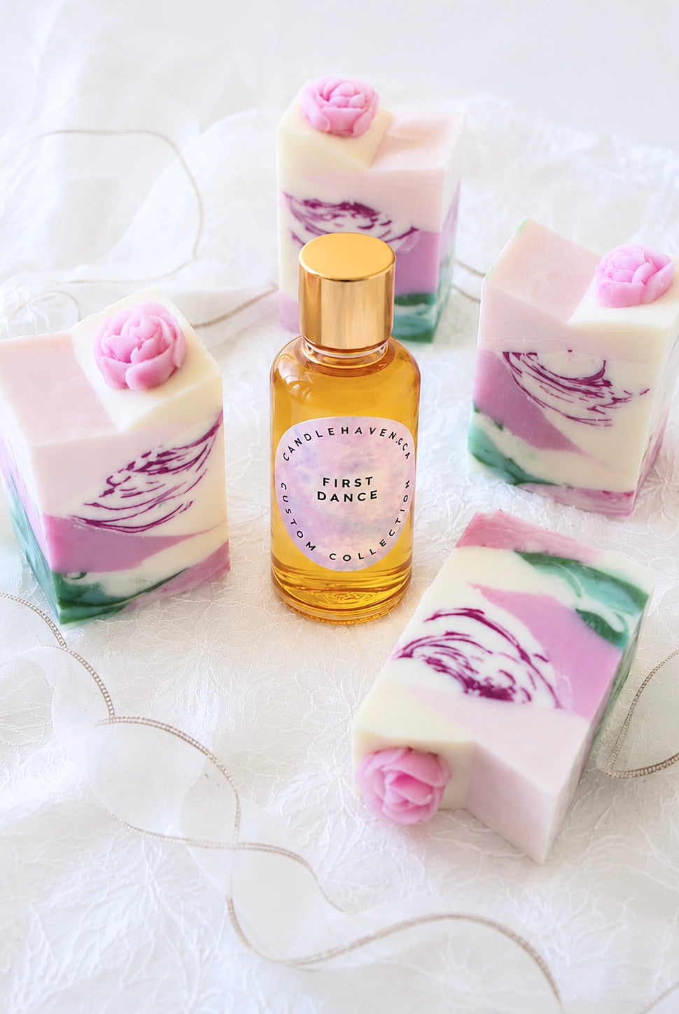 Bottle of 'First Dance' fragrance oil by Candlehaven.ca with floral soap bars on a white background