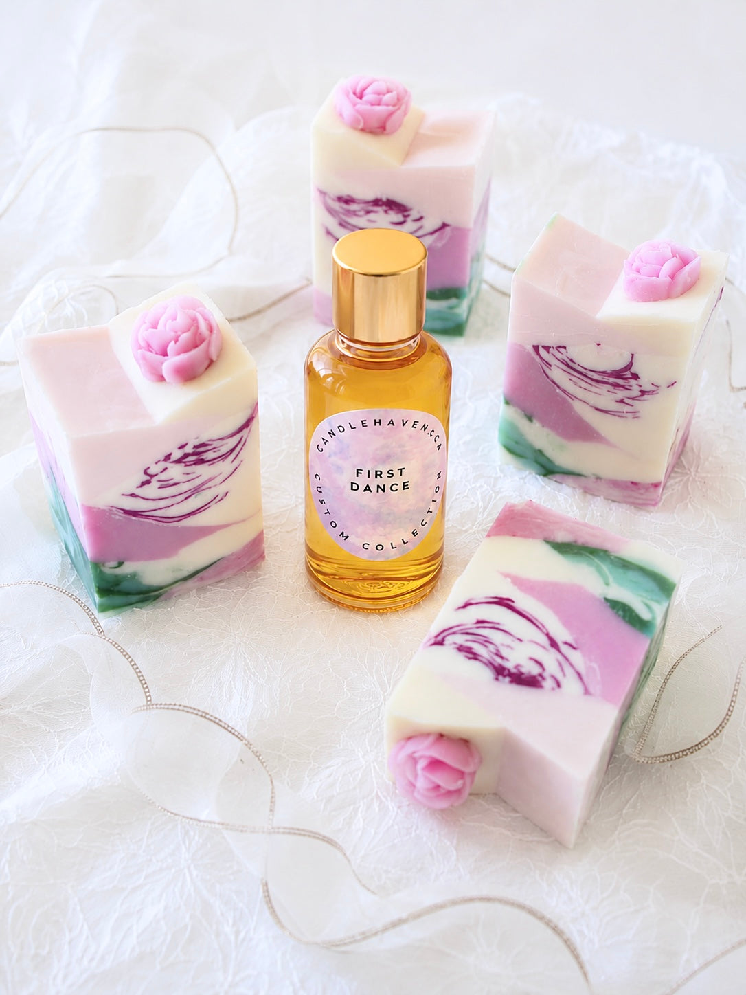 Bottle of 'First Dance' fragrance oil by Candlehaven.ca with floral soap bars on a white background