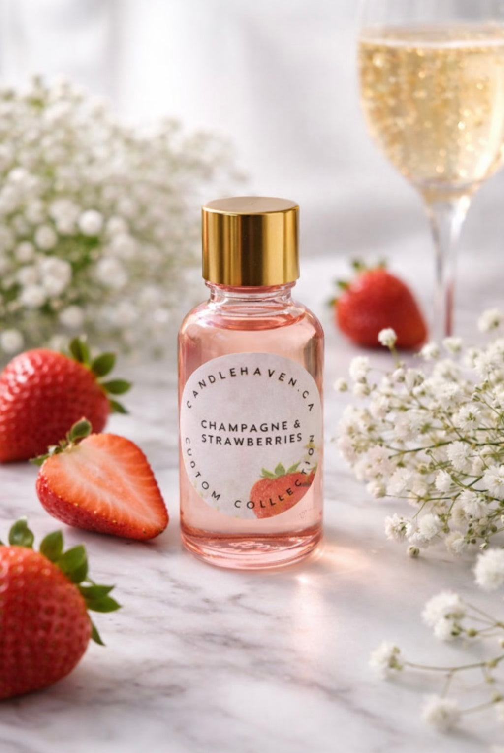 Bottle of Candlehaven.ca’s 'Champagne & Strawberries' perfume with strawberries and flowers on a marble surface