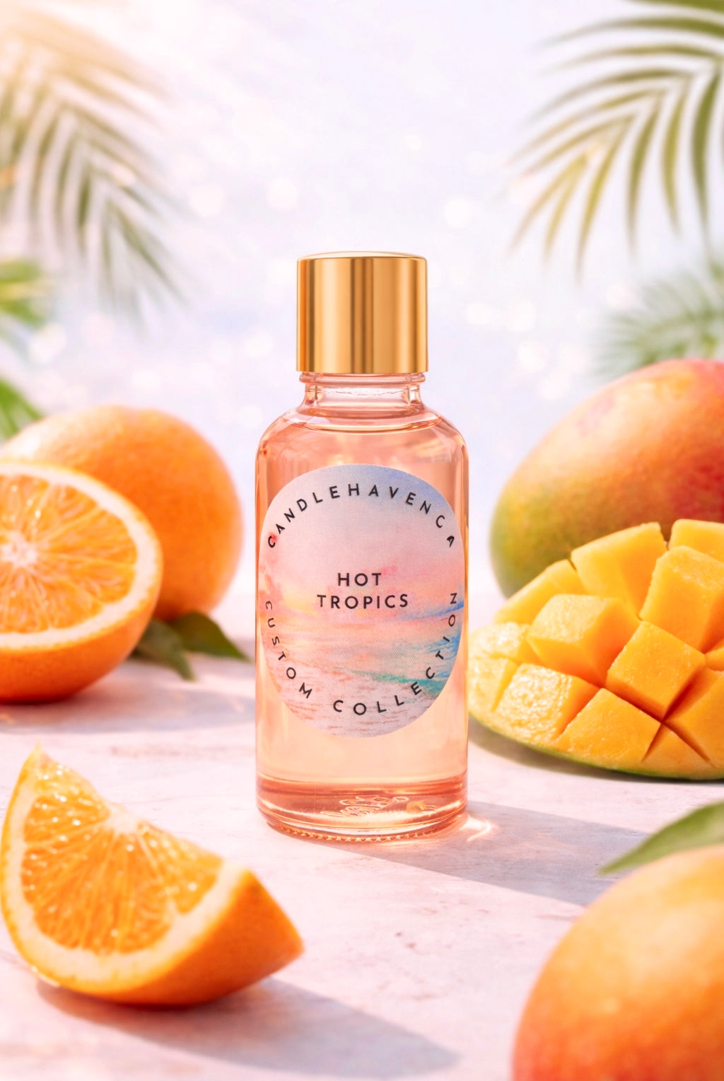 Pink candle fragrance oil bottle labeled 'Hot Tropics' surrounded by oranges and mangoes on a light background