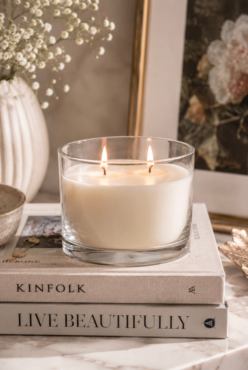 Candle in a glass holder on top of books with decorative elements in the background