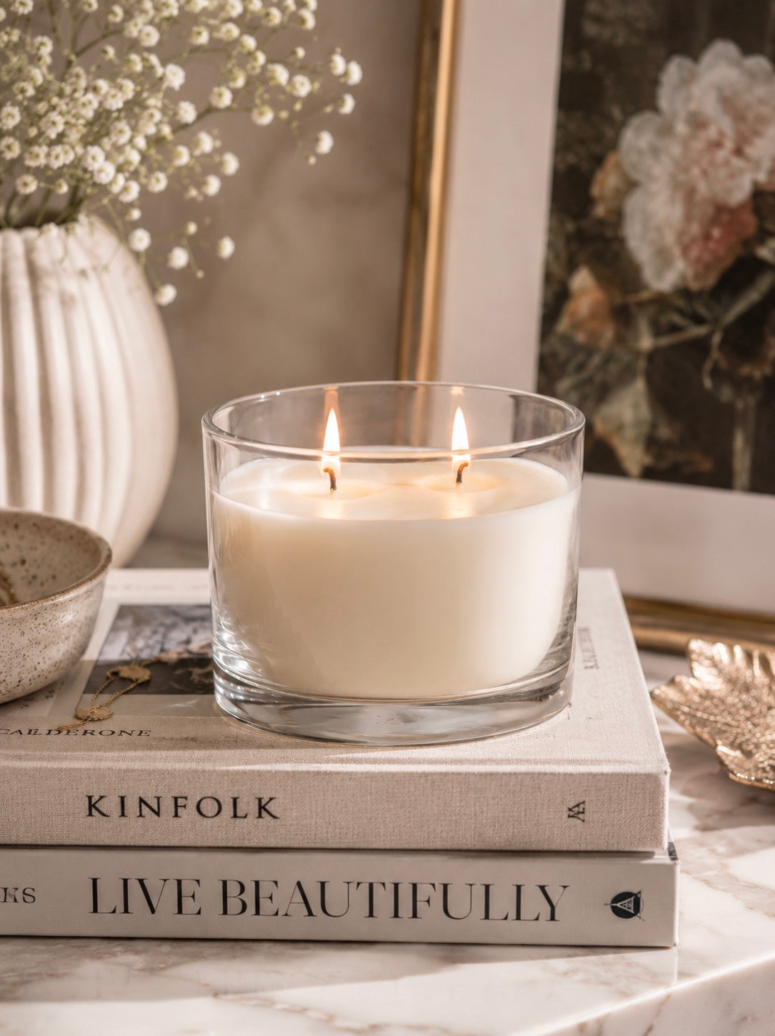 Candle in a glass holder on top of books with decorative elements in the background