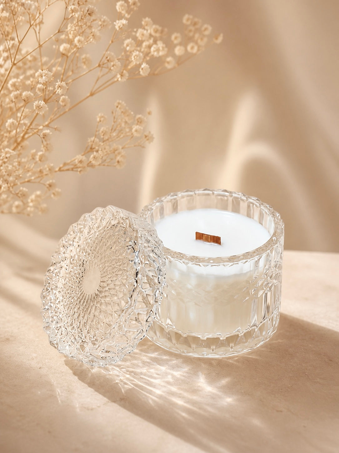 Clear vessel with lid with wax and wood wick inside on a light background
