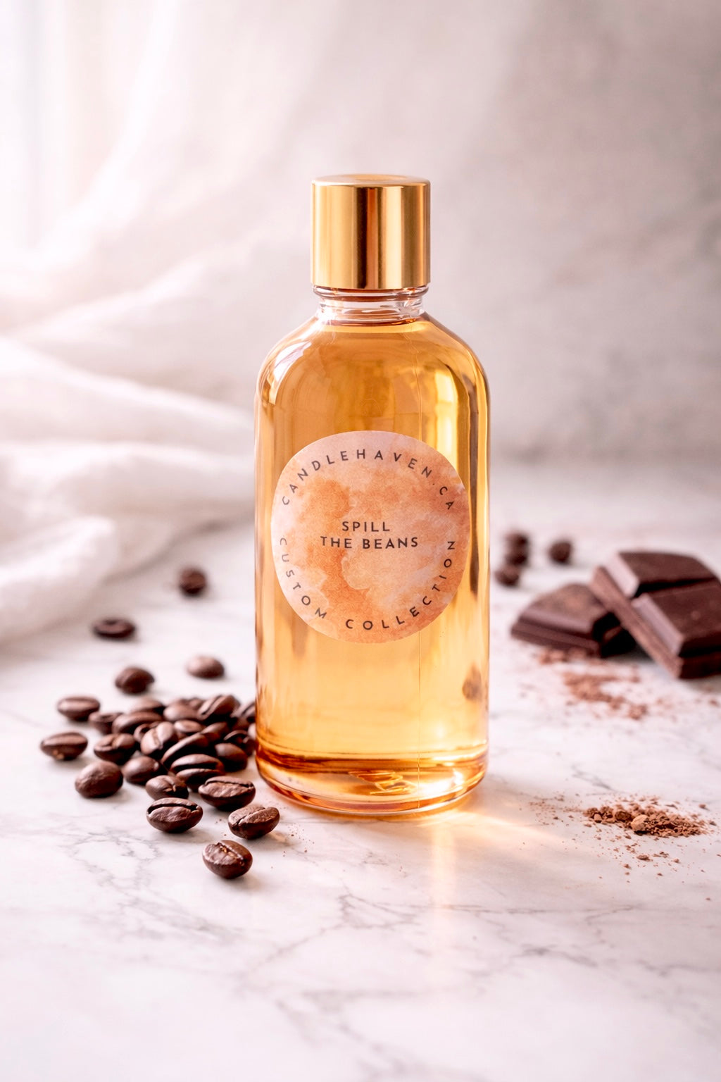 Bottle of 'Spill the Beans' fragrance oil by Candlehaven on a marble surface with coffee beans and chocolate.