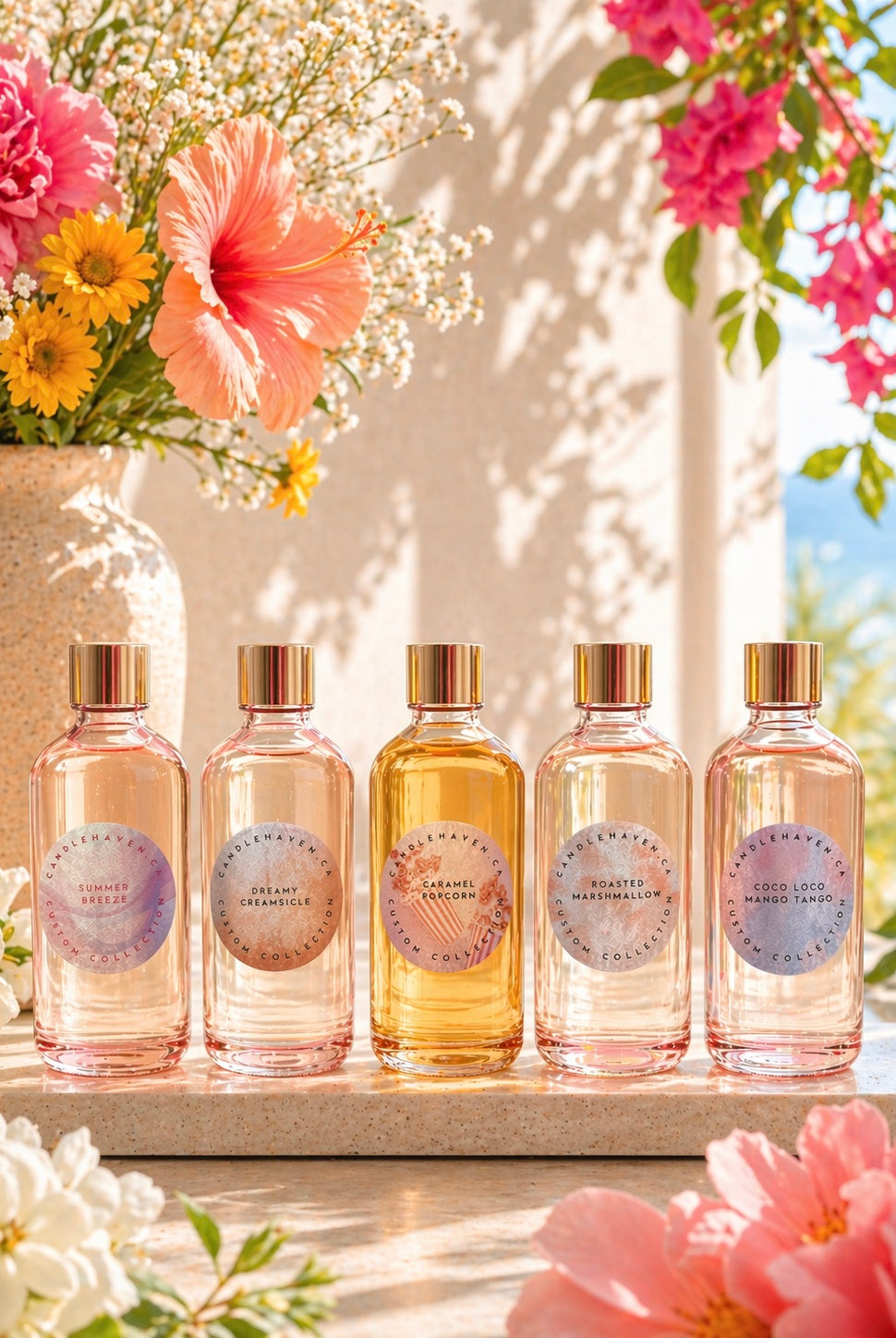 Five candle fragrance oil bottles with circular labels on a wooden surface, surrounded by flowers.
