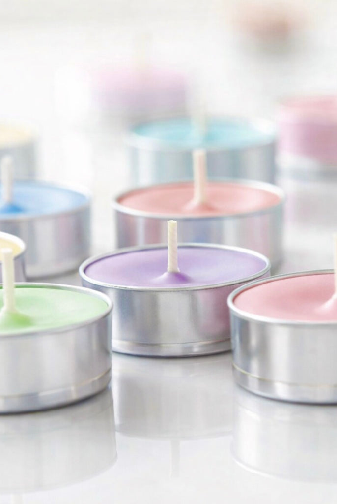 Pastel-colored tealight candles in tealight cups on a white background