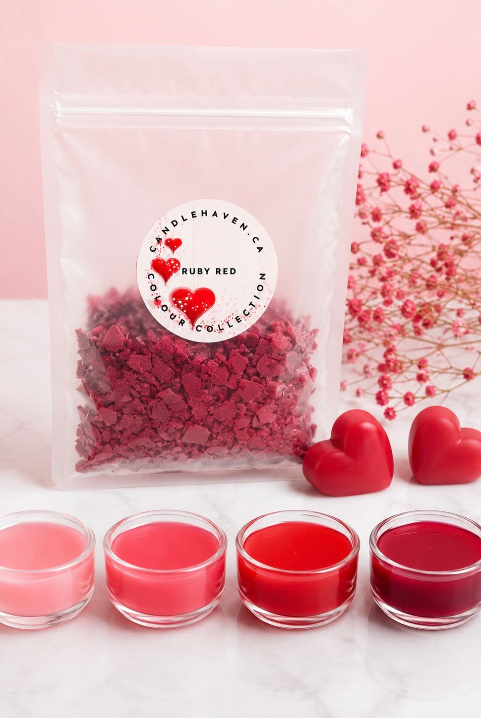 Candleaven Co. Ruby Red wax dye chips with jars full of wax and heart-shaped candles on a light pink background