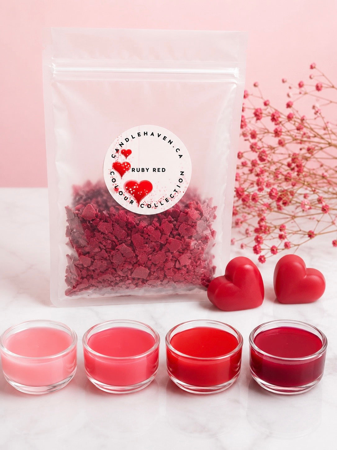 Candleaven Co. Ruby Red wax dye chips with jars full of wax and heart-shaped candles on a light pink background