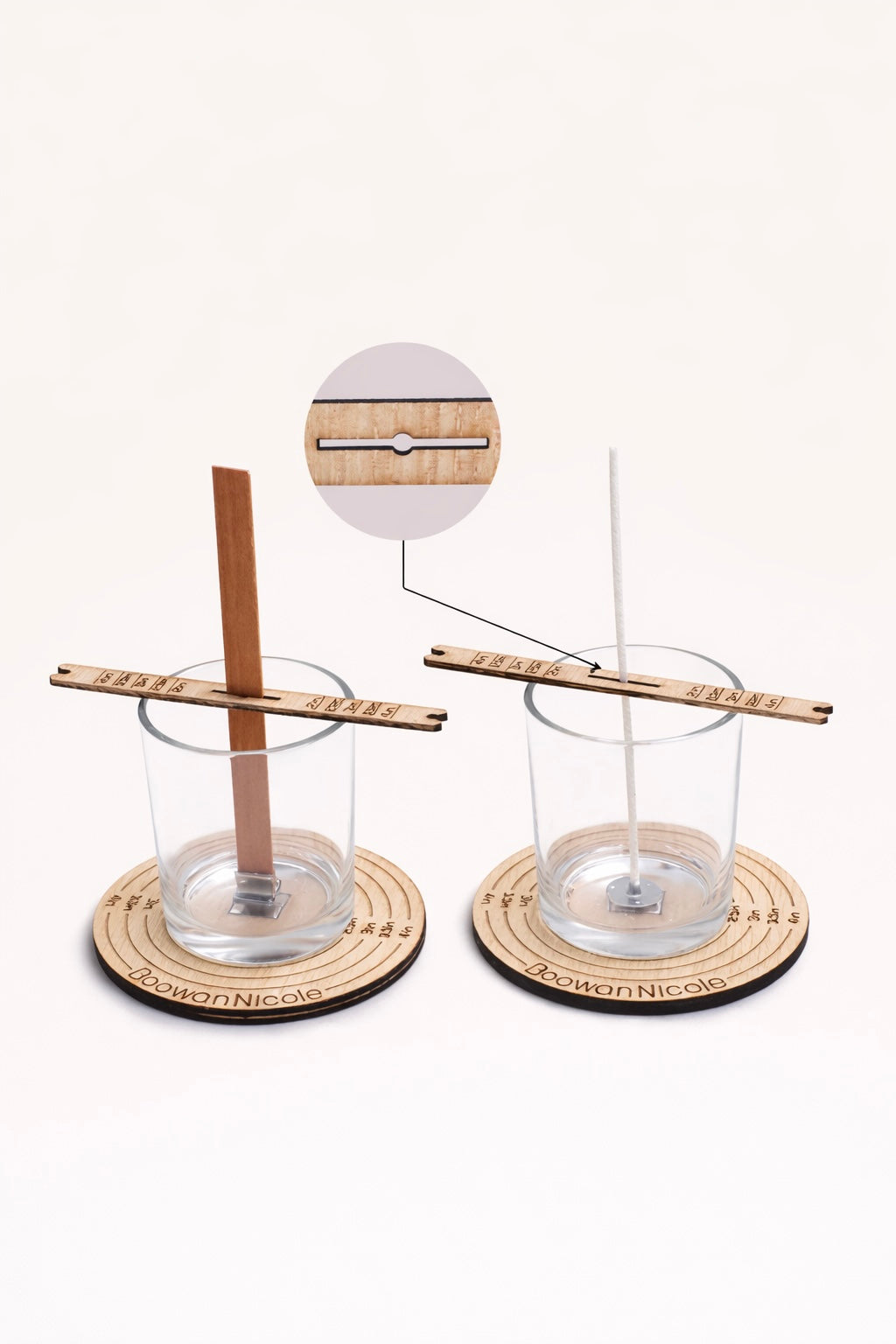 Two glass candle vessels with wooden wick setters on round wick centering tools with a white background