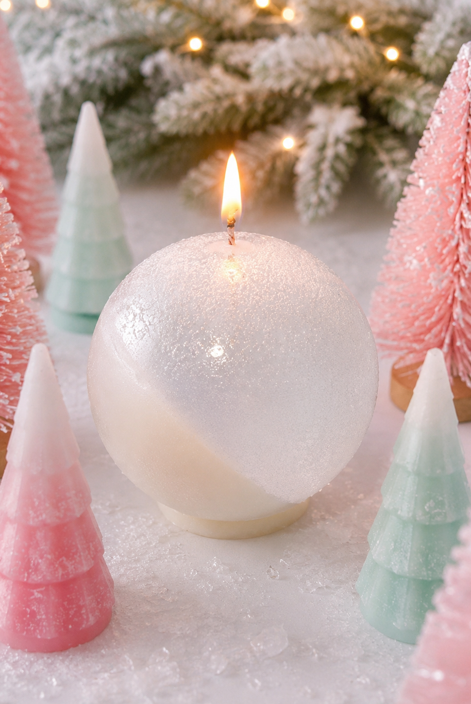 Decorative Christmas scene with a white candle, pink and green trees, and snow-like surface.