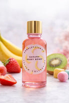 Bottle of 'Banana Berry Bomb' fragrance oil for candle making with fruit-themed packaging on a light background