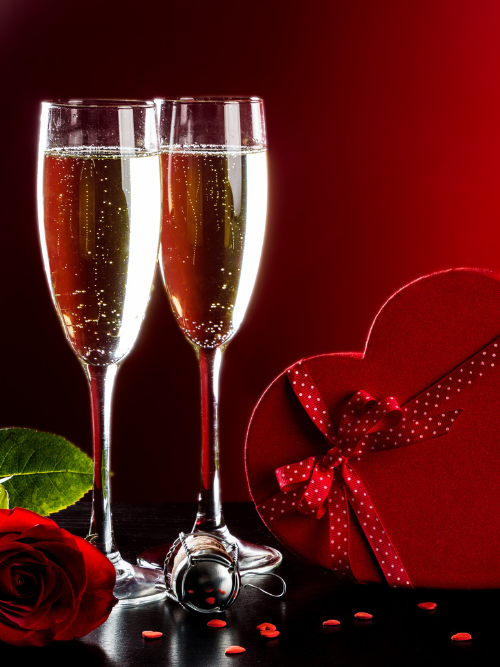 Champagne Toast Fragrance Oil | Two champagne glasses with a red heart-shaped gift box and rose on a dark background