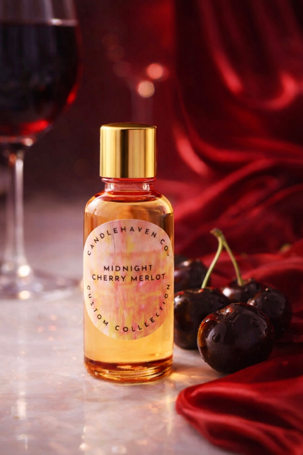 Bottle of Candlehaven’s ‘Midnight Cherry Merlot' candle fragrance oil with cherries and a glass of wine on a red fabric background
