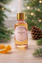 Bottle of Candlehaven Christmas Fir fragrance on a wooden surface with festive decorations.