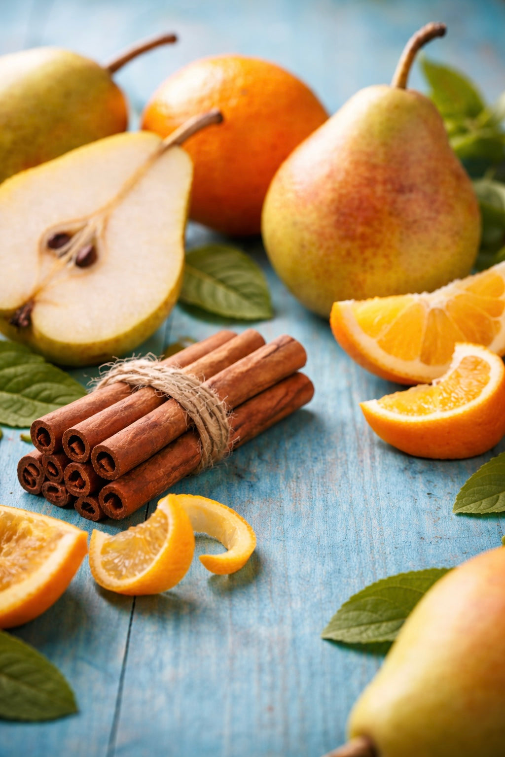Pears, oranges, and cinnamon sticks on a blue wooden surface depicting a fragrance oil for soap and candle making from candlehaven