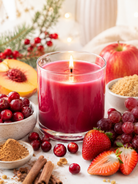 Cranberry scented candle surrounded by fruits and spices on a wooden surface