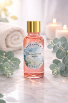 Bottle of Candlehaven.ca’s Eucalyptus Noir candle making fragrance oil with gold cap on a marble surface with eucalyptus leaves.