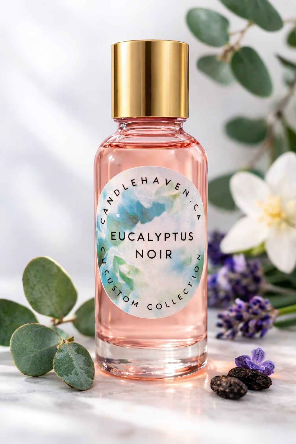 Pink bottle with gold cap labeled 'Eucalyptus Noir' by Candlehaven on a marble surface with greenery and flowers.
