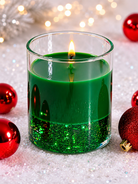 Green candle in a glass container with red ornaments on a glittery surface