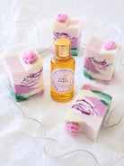 Bottle of 'First Dance' fragrance oil by Candlehaven.ca with floral soap bars on a white background