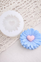 Blue wax flower with a pink heart center on a white lace background