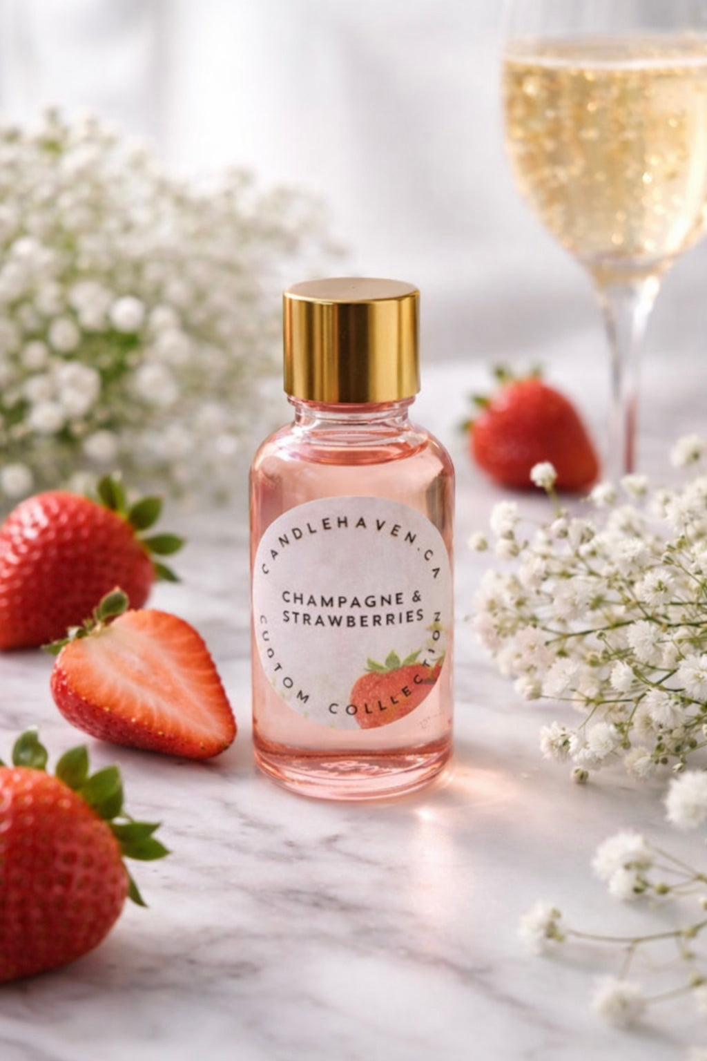 Bottle of Candlehaven.ca’s 'Champagne & Strawberries' perfume with strawberries and flowers on a marble surface