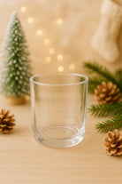 Aura Vessels Canada | Clear glass Gaia Vessel on a wooden surface with Christmas decorations including a small tree, pinecones, and lights.