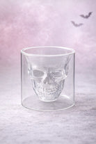 Glass skull vessel on a light purple background with bats.