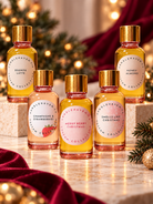 A collection of five different holiday fragrance oils used in candle making on a Christmas themed background. 
