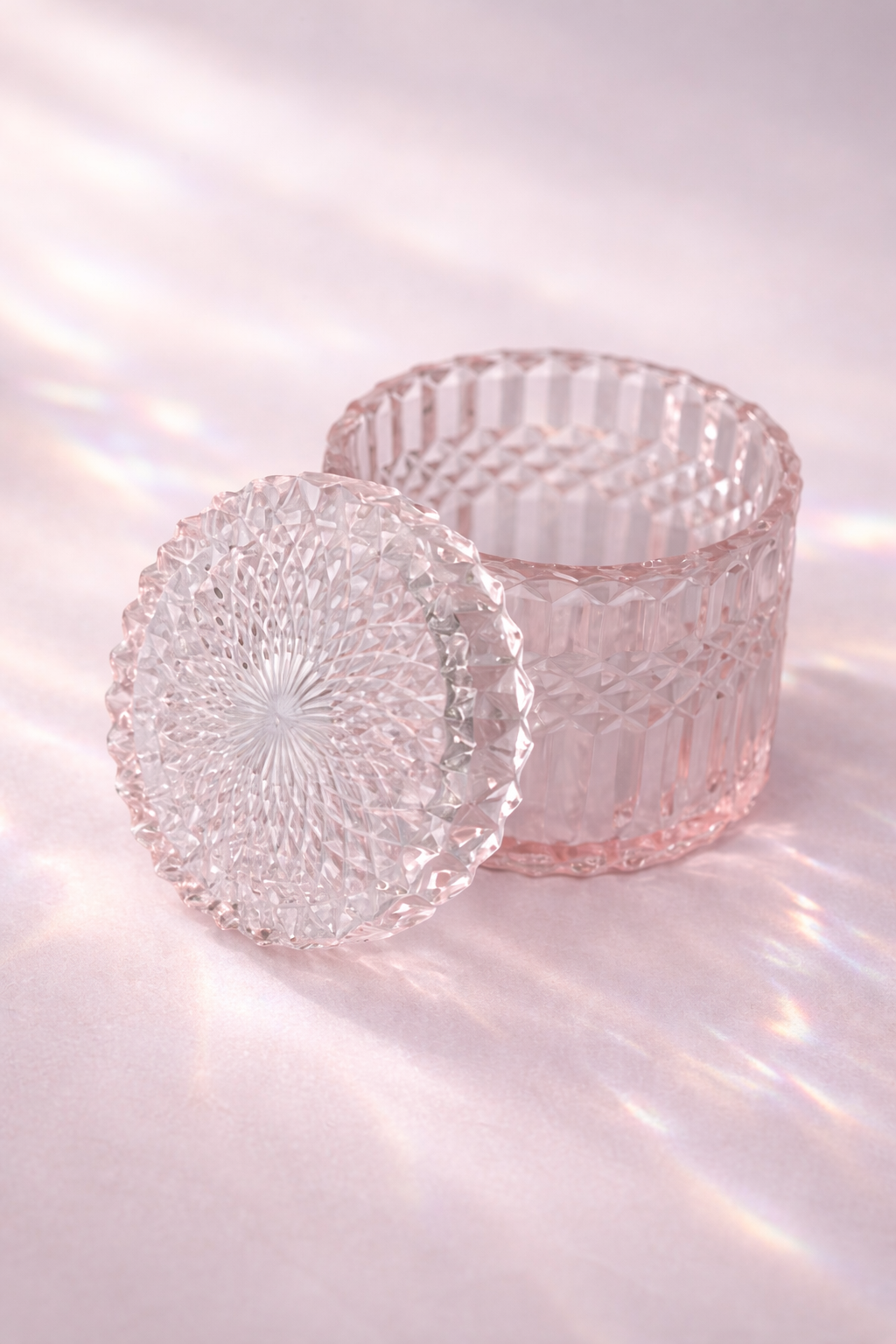 pink glass candle holders with textured designs on a reflective surface.