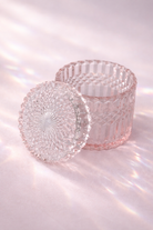 pink glass candle holders with textured designs on a reflective surface.
