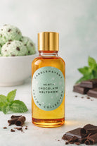 Bottle of Candlehaven.ca’s Mint Chocolate Meltdown candle fragrance oil with mint leaves, chocolate pieces, and a bowl in the background.