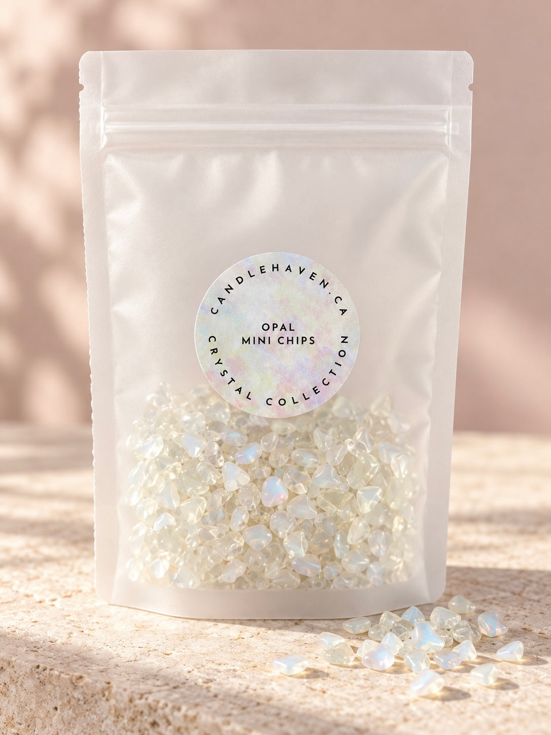 A white stand-up pouch labeled 'Candlehaven Crystal Collection Opal Mini Chips' filled with small iridescent crystal chips, standing on a stone surface with a soft beige background.