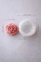 Pink peony shaped mold and white silicone mold with measurements on a gray background
