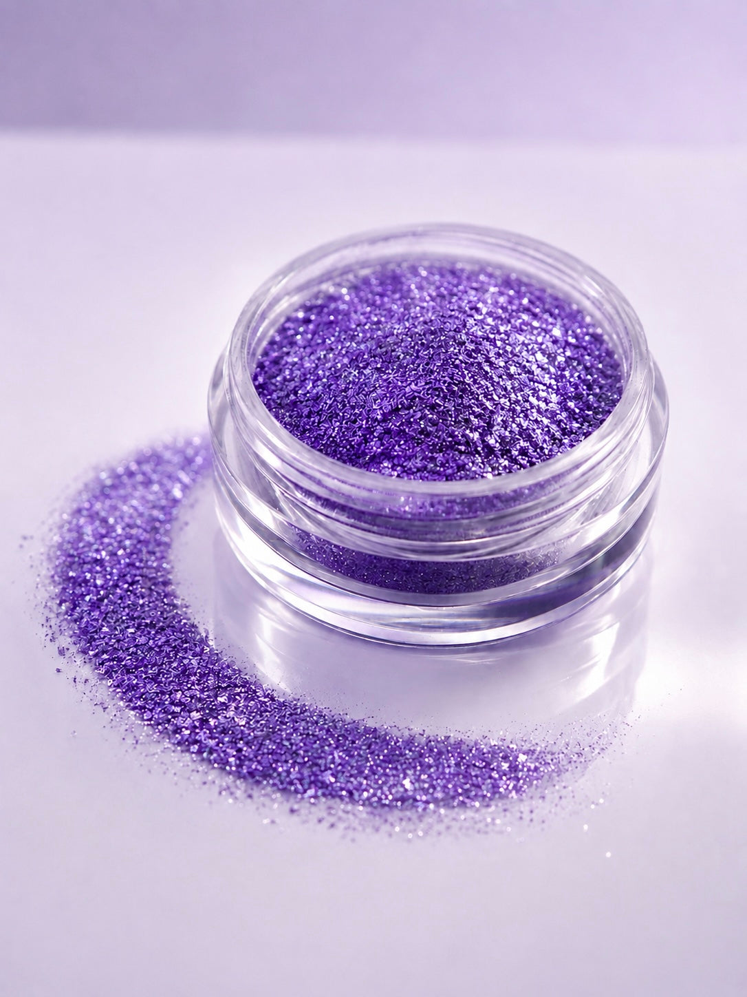 A small clear round jar filled with sparkling purple diamond sparkle dust, with additional loose purple diamond sparkle dust spilled in a curved line beside it on a pale lavender background.