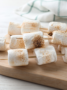 Roasted Marshmallows on skewers with grill marks on a wooden board representing roasted marshmallow fragrance oil for candle making