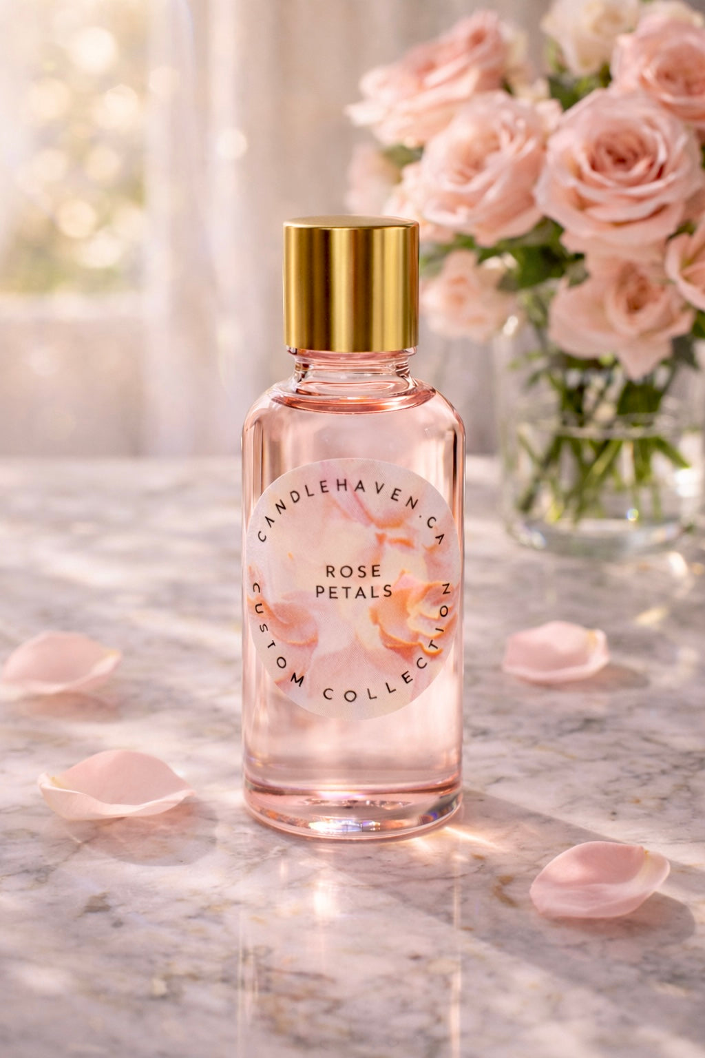 Pink bottle labeled 'Rose Petals' by Candlehaven on a marble surface with rose petals and a blurred background of flowers.