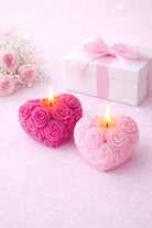Heart-shaped candles with rose designs on a light pink background with a gift box and flowers.