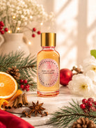Fragrance oil bottle labeled 'Smells Like Christmas' by Candlehaven.ca surrounded by festive decorations on a wooden surface.