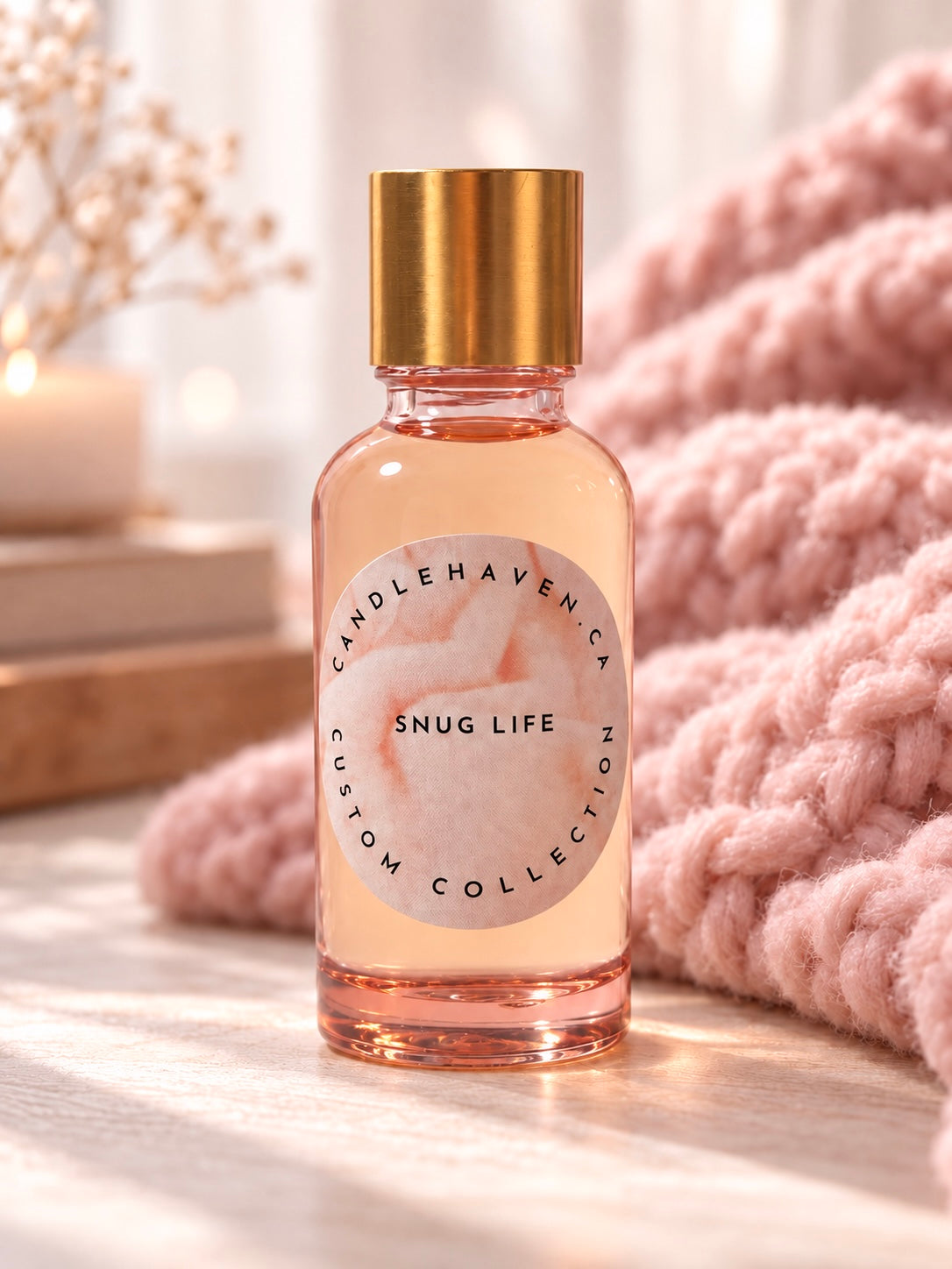A bottle of snug life fragrance oil for candle making in front of a snuggly pink blanket 