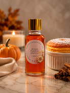 Bottle of spiced pumpkin souffle fragrance oil with a pumpkin, candle, and dessert in the background.