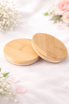 Two wooden lids for candle vessels on a light surface with floral decorations