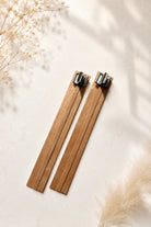 Two wooden wicks for candle making with metal wick clips on a light background with dried baby’s breath