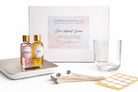 Candle-making kit with wax,  fragrance oils, a scale, glass vessel, wicks, and wick stickers on a white background.